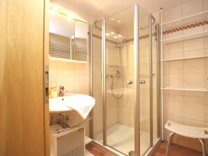 Ein Badezimmer mit Duschkabine, Waschbecken mit Handtuch und Ablagefläche.