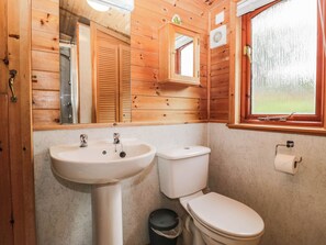 A wooden-paneled bathroom with a sink, toilet, and window. - 89 Ambleside (Windermere)