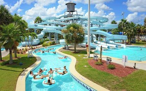 En vattenpark med en stor pool, flera vattenrutschkanor och folk som åker på uppblåsbara badringar.