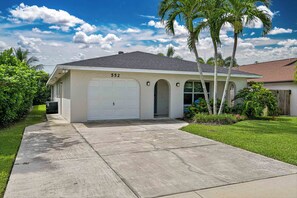 A single-story house with a garage, numbered 552, surrounded by a well-maintained lawn and palm trees. - Shore Thing at Vanderbilt – Naples Park Retreat, Bike to the Beach! (Naples)