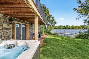 Una casa con jacuzzi, un muro de piedra y un muelle que se adentra en un lago.