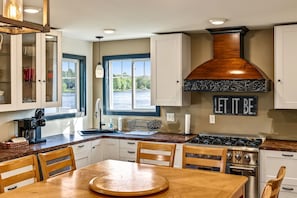 A modern kitchen with a central island, a stove, and a window overlooking a body of water. - Winter Lakeside Lodge on Lake Winter | Hot Tub | Trail Access | Dog Friendly (Winter)