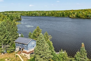 A house with a deck overlooking a large lake surrounded by dense forest. - Winter Lakeside Lodge on Lake Winter | Hot Tub | Trail Access | Dog Friendly (Winter)