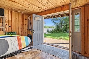 A wooden interior with a door leading outside, a surfboard, and a kayak. - Winter Lakeside Lodge on Lake Winter | Hot Tub | Trail Access | Dog Friendly (Winter)