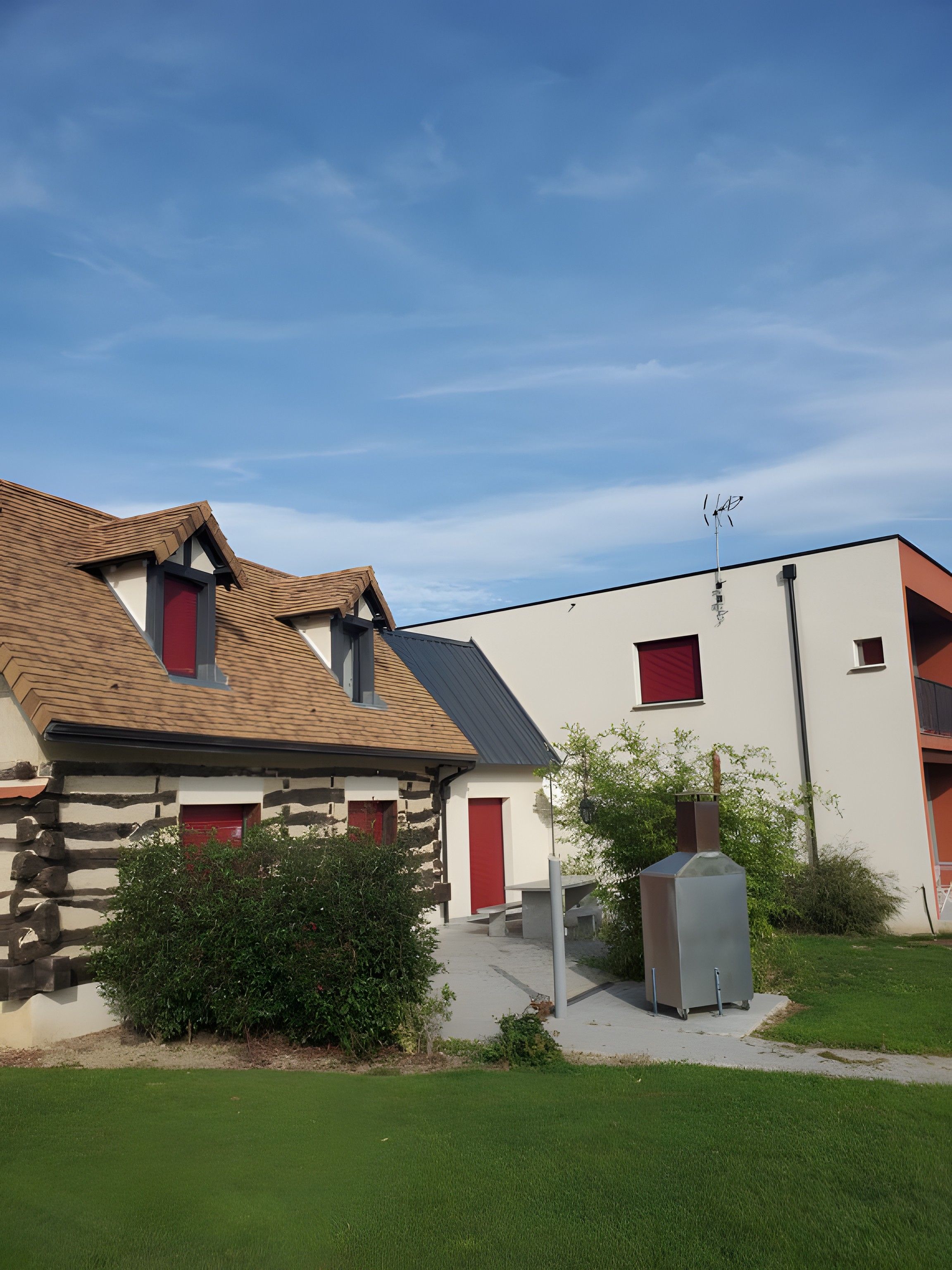 Un bâtiment à deux étages, doté d’un toit en pente, d’une cheminée et d’une porte rouge.