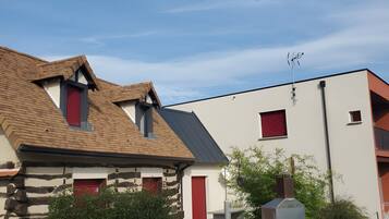 Un bâtiment à deux étages, doté d’un toit en pente, d’une cheminée et d’une porte rouge.