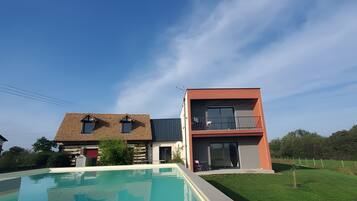 Une maison moderne dotée d’une piscine, d’un balcon et d’une pelouse bien entretenue.