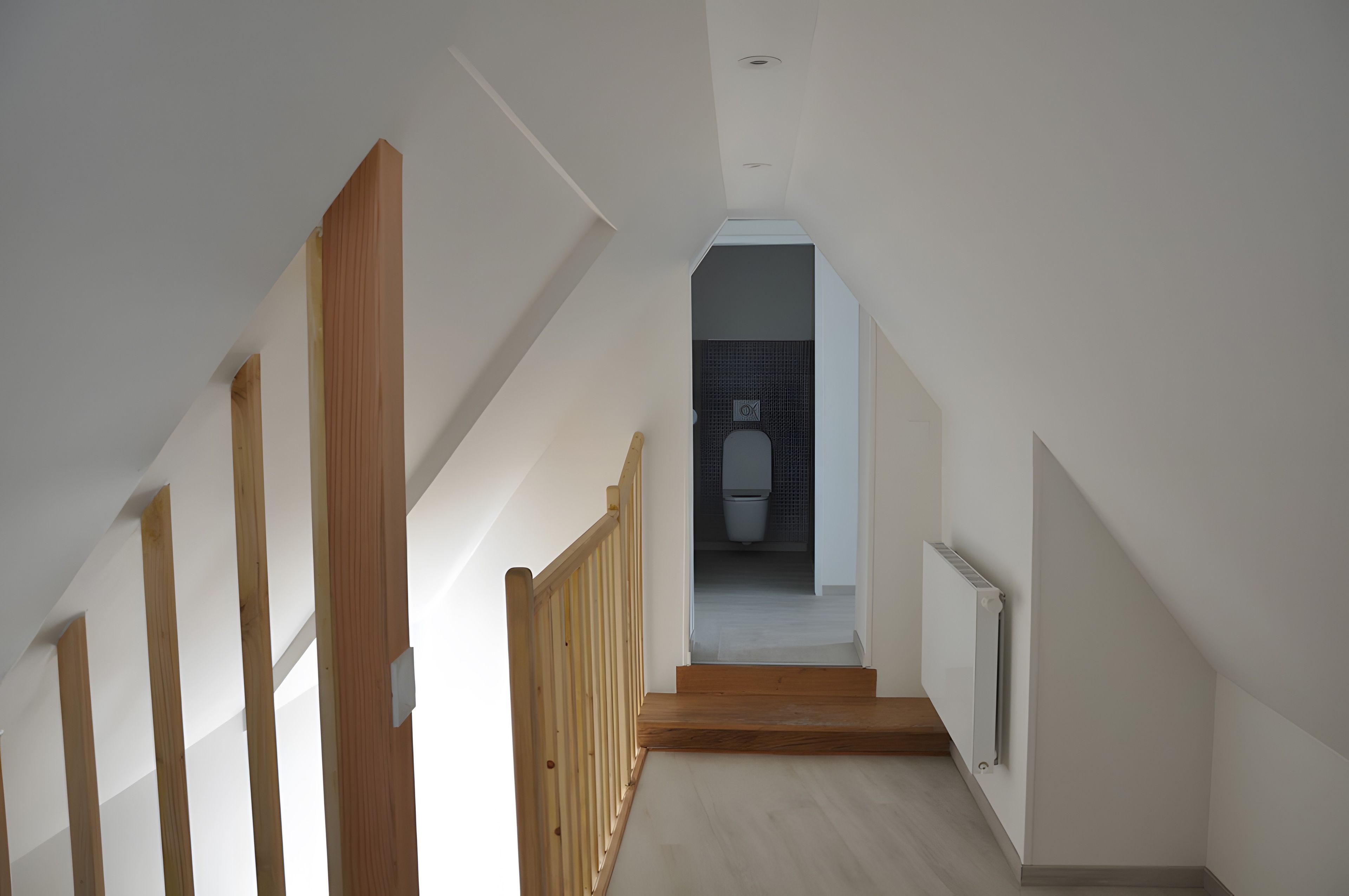 Una escalera conduce a un baño con un inodoro y un radiador.