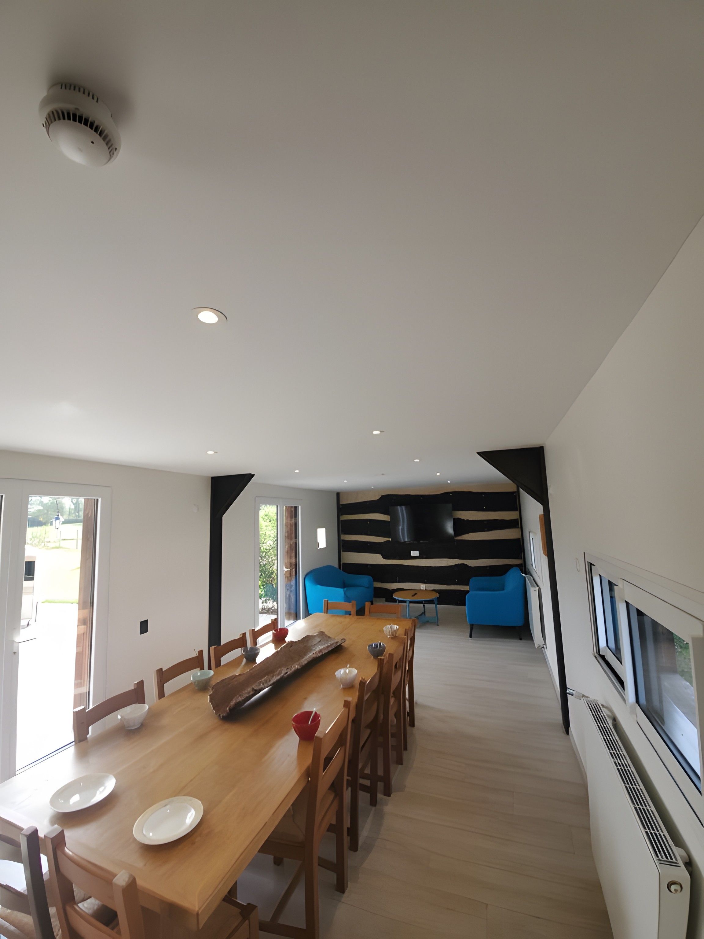 Un espace de repas moderne avec une table en bois, des chaises et un canapé bleu en arrière-plan.