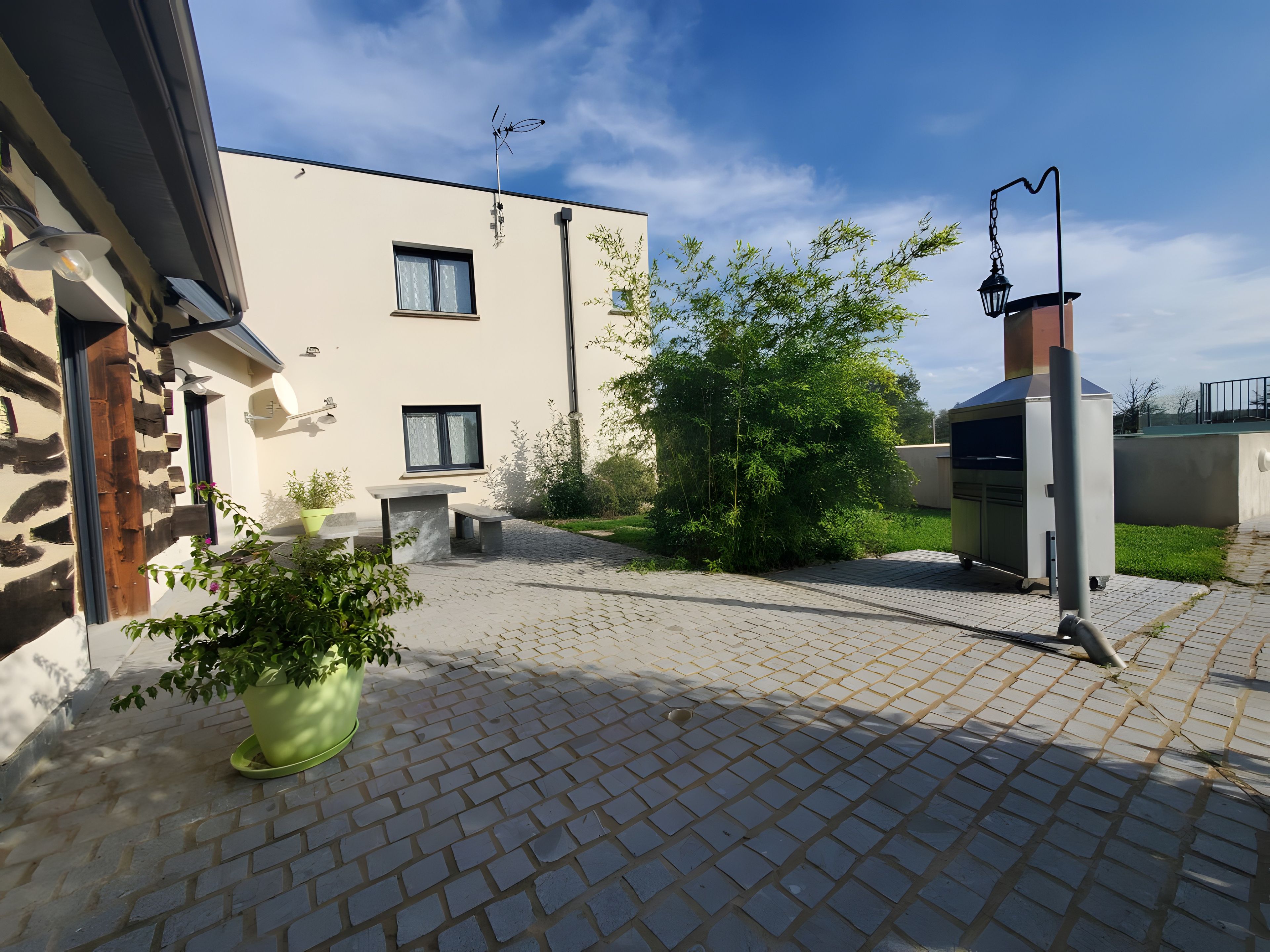 A patio with a barbecue grill, a potted plant, and a stone wall.