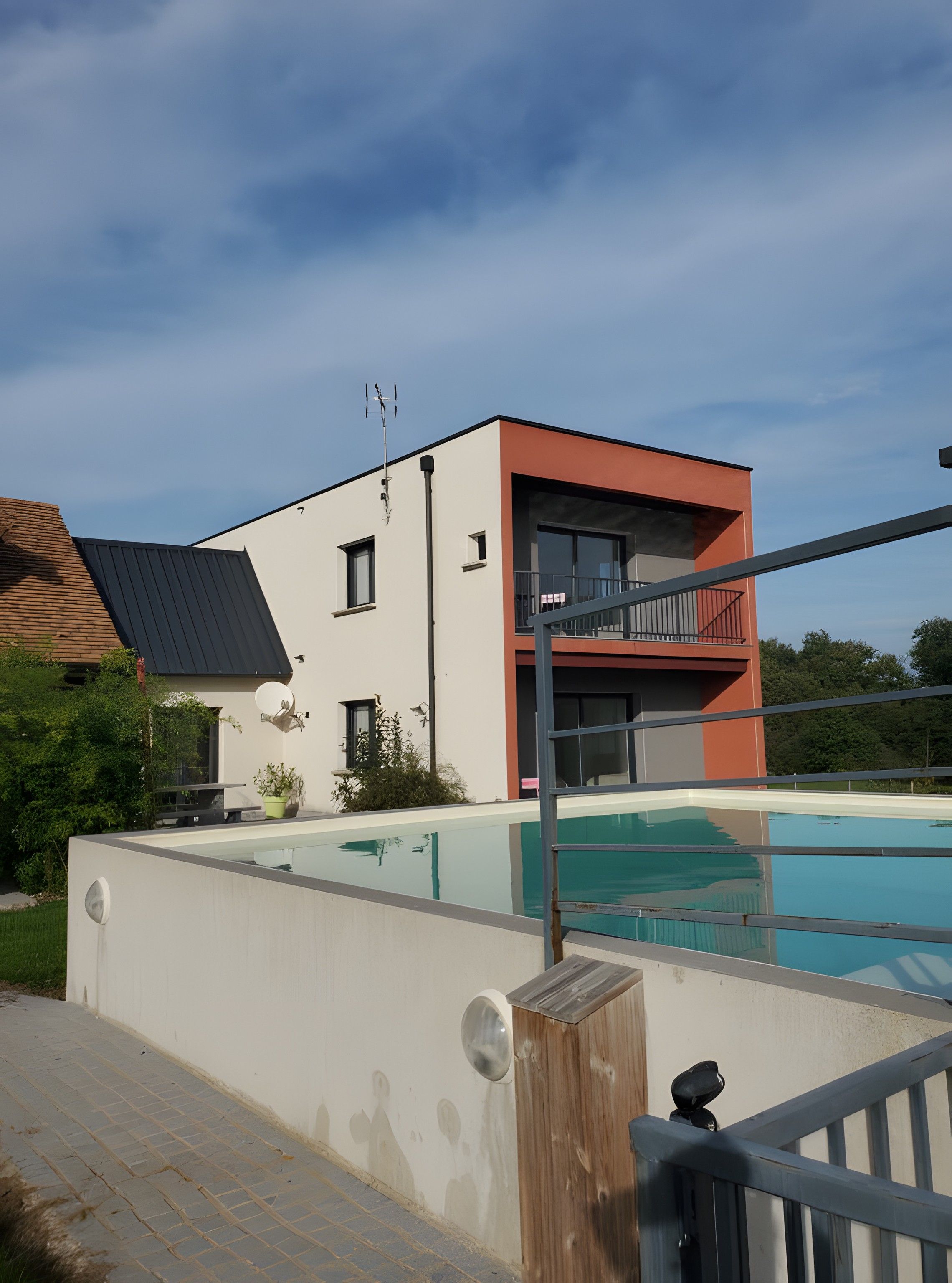 Un edificio moderno de dos plantas con piscina, balcón y antena parabólica.