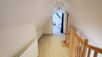 A modern interior with a wooden staircase, white walls, and a visible radiator.
