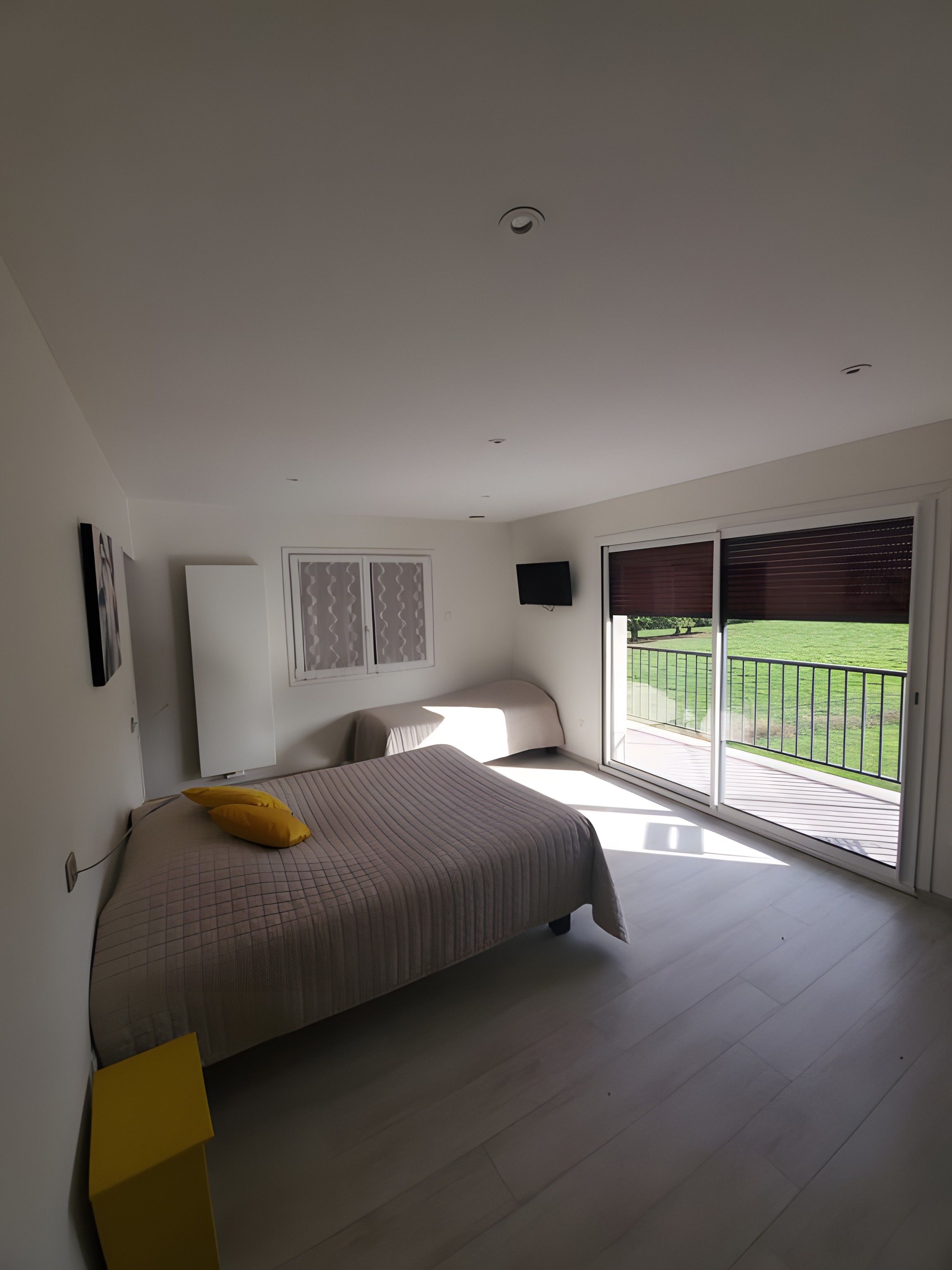 Une chambre à coucher avec un lit, une télévision et un balcon donnant sur un paysage verdoyant.
