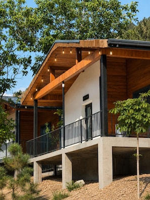 A modern building with a wooden facade, a balcony with a railing, and a clear sky. - Oxygen garden (Yangiabad)