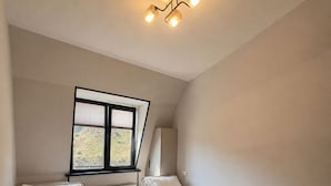 A bedroom with two beds, a window, and a ceiling light fixture. - Oxygen garden (Yangiabad)