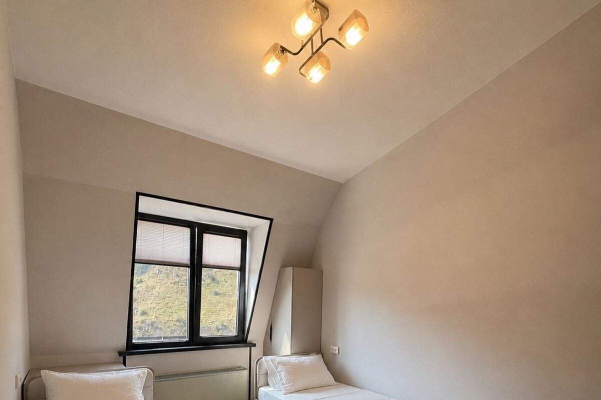 A bedroom with two beds, a window, and a ceiling light fixture.
