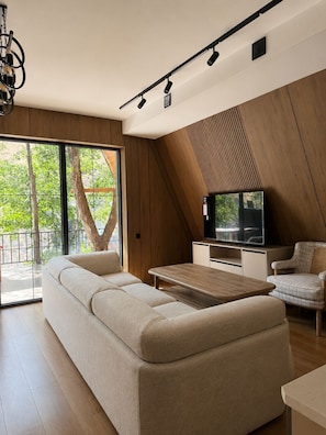 A modern living room with a sofa, a coffee table, and a television. - Oxygen garden (Yangiabad)