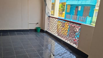 Un suelo de baldosas con superficie reflectante, un cubo verde y una pared con un estampado geométrico de colores.
