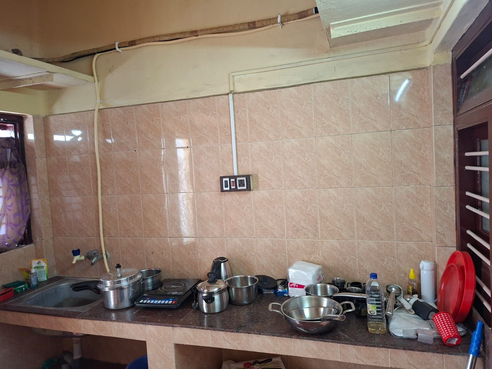 Una cocina con salpicadero de azulejos, un lavamanos y diferentes utensilios y electrodomésticos de cocina.