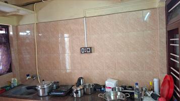 Una cocina con salpicadero de azulejos, un lavamanos y diferentes utensilios y electrodomésticos de cocina.