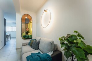 Een moderne woonkamer met een bank, een grote spiegel en een potplant.