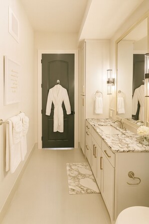 A hotel bathroom with a marble countertop, a large mirror, and a towel rack. - 2 Bedrooms • 2 Full Bathrooms • King + Queen Beds • Prime Frisco Location (Frisco)