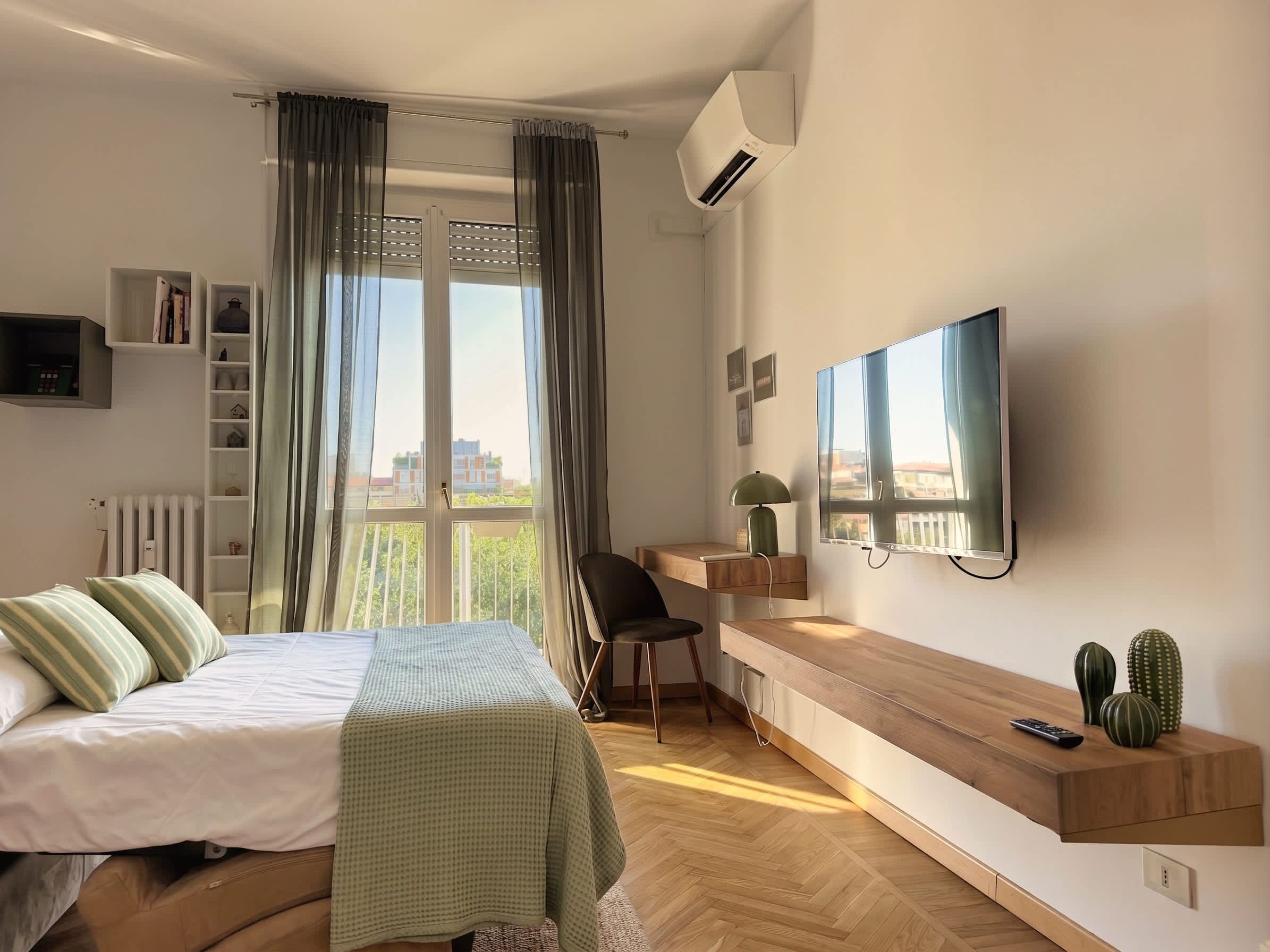 Ein modernes Schlafzimmer mit einem Bett, einem Schreibtisch, einem Stuhl, einem Fernseher und einem Fenster mit Vorhängen.