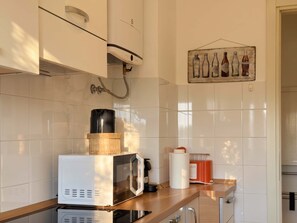 A kitchen with a microwave, coffee maker, and a wall-mounted water dispenser. - The Washington Studio Apartment - with balcony (Milano)