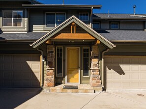 A residential house with a front entrance, a garage, and a stone pillar. - 2BR Park City townhome in Kimball Junction with mountain views. (Park City)