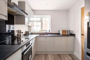 A modern kitchen with a built-in oven, a microwave, and a sink. - House Sleeps 8 With Hot Tub and Parking (Colchester)