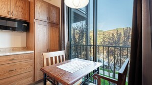 Una cocina con armarios de madera y una mesa de comedor con vistas a un balcón.