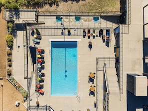 An aerial view of a swimming pool area with multiple lounge chairs and a staircase leading to a rooftop deck. - Studio in Deer Valley East Village with pool, hot tub, gym, and ski access. (Heber City)