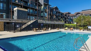 Un hotel con piscina, zona de estar exterior y una escalera que conduce a los pisos superiores.