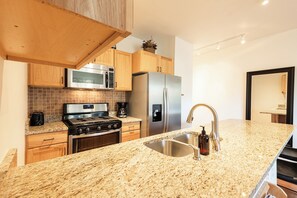 Eine moderne Küche mit Granit-Arbeitsplatten, Edelstahlgeräten und Holzschränken.