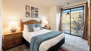 Quarto com cama, mesas de cabeceira, janela com vista e decoração nas paredes.