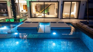 Een modern buitenzwembadgedeelte met twee ligbedden en een glazen patio.