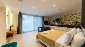 Een moderne slaapkamer met een groot bed, een vrijstaand bad, een wastafel met spiegel en een wand met steenmotief.