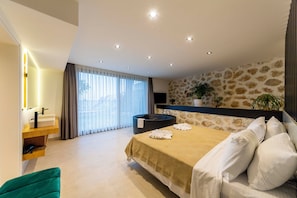 Quarto moderno com cama grande, banheira integrada, toucador com espelho e parede com padrão de pedra.