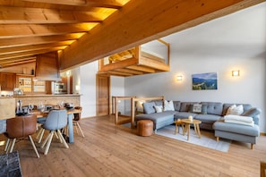 A modern interior with a dining area, kitchen, and living space with a large sofa and a view of the outdoors. - Echo 8 - Sleeps 7 - Magnificent Luxury Penthouse (Haute-Nendaz)