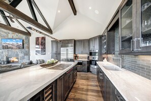 Une cuisine moderne avec une cheminée en pierre, des appareils électroménagers en acier inoxydable et un long plan de travail.