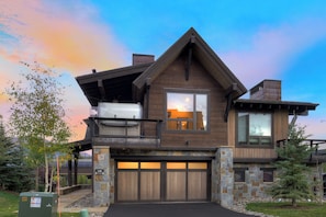 A two-story house with a garage, a balcony, and a stone facade. - 🏆 Falcon Haus MidStation Gondola | 2 Hot Tubs | Sleeps 10 (Breckenridge)