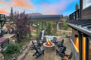 An outdoor patio area with a fire pit, seating, and a view of the mountains. - 🏆 Falcon Haus MidStation Gondola | 2 Hot Tubs | Sleeps 10 (Breckenridge)