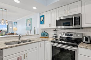 A modern kitchen with white cabinetry, stainless steel appliances, and a granite countertop. - Heron Walk 8986 Golf Cart, Pool, Sleeps 6 (Miramar Beach)