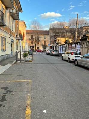 Una calle con coches aparcados y edificios a ambos lados.