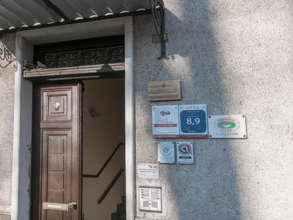 A building entrance with a wooden door, a staircase, and several plaques on the wall.
