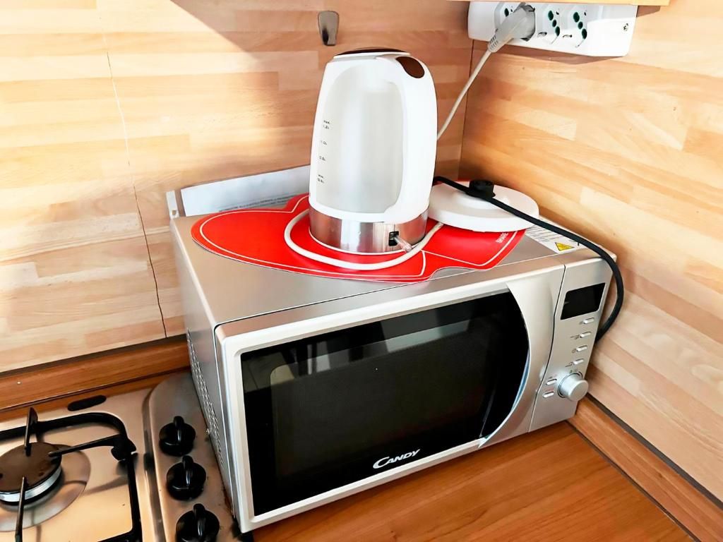 A microwave oven with a red tray insert and a white electric kettle on top.