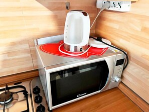 A microwave oven with a red tray insert and a white electric kettle on top. - Il Broletto B&B (Novara)