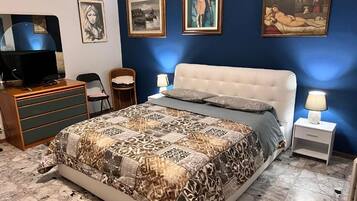 Un dormitorio con cama, televisión, escritorio y sillas.