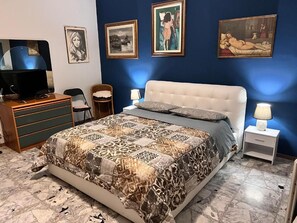 A bedroom with a bed, a television, a desk, and chairs. - Il Broletto B&B (Novara)