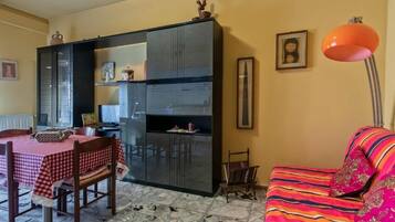 Un espacio habitable compacto con comedor, kitchenette y un sofá con una manta colorida.
